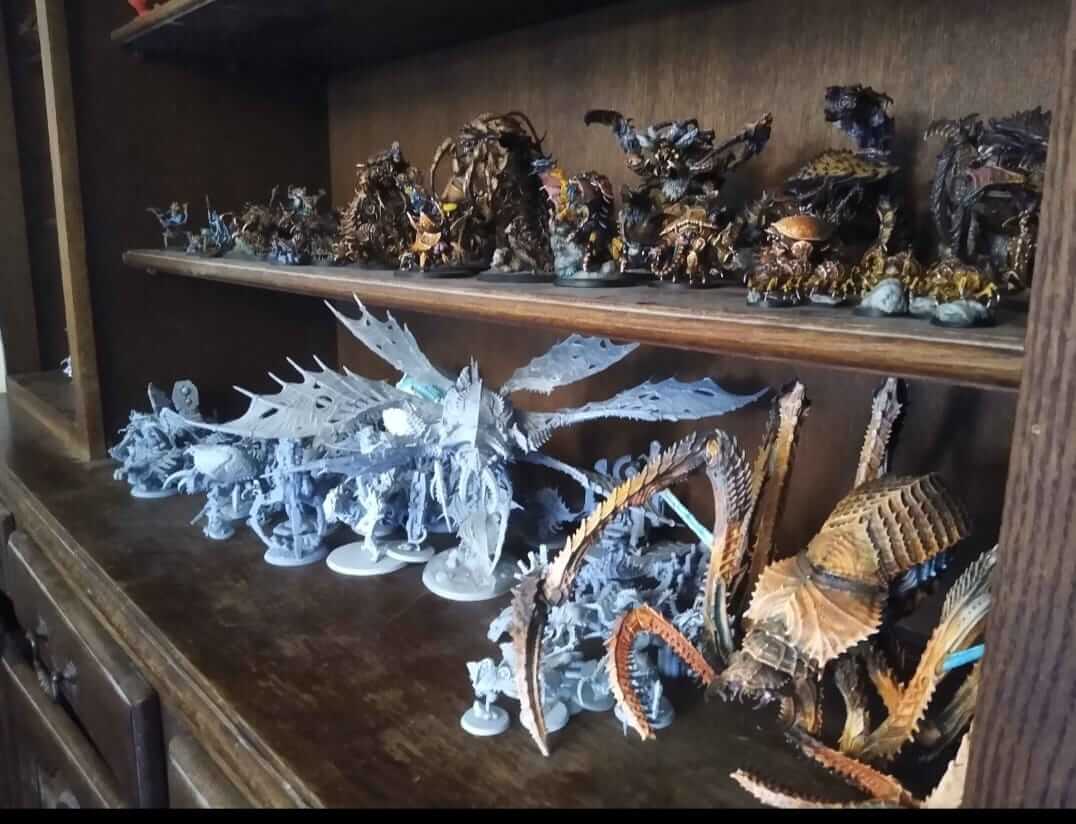 Collection of detailed miniature figures displayed on a wooden shelf, showcasing various fantasy designs.